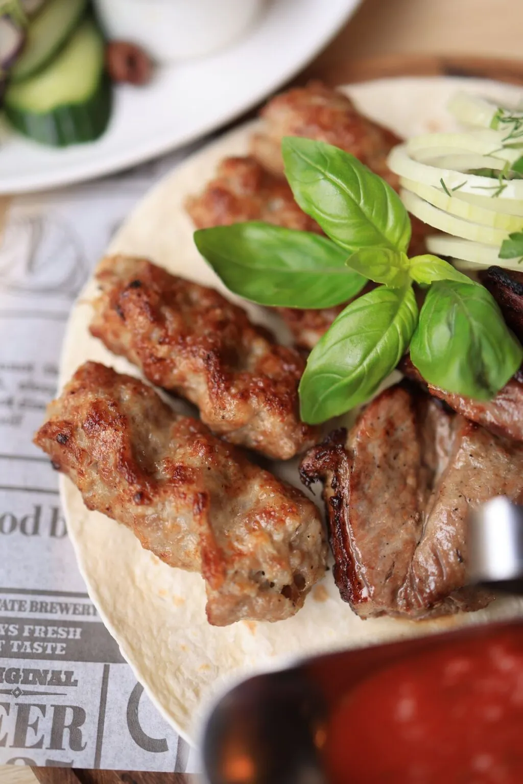 Bucăți de carne rumenite pe grătarul încins, cu jar acoperit de cenușă albă