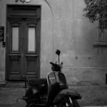 Motocicletă de turism oprită pe un drum montan cu serpentine și piscuri în fundal